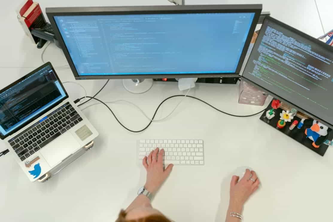 Overhead view of a coding workspace with multiple monitors