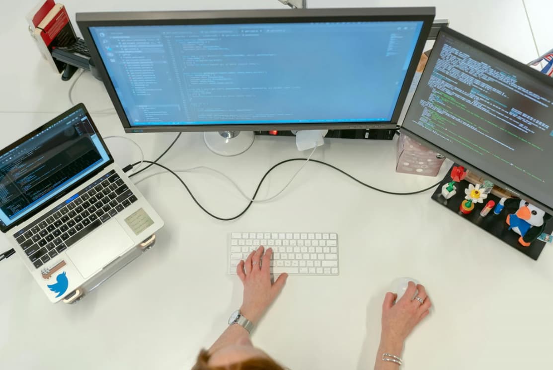 Overhead view of a coding workspace with multiple monitors